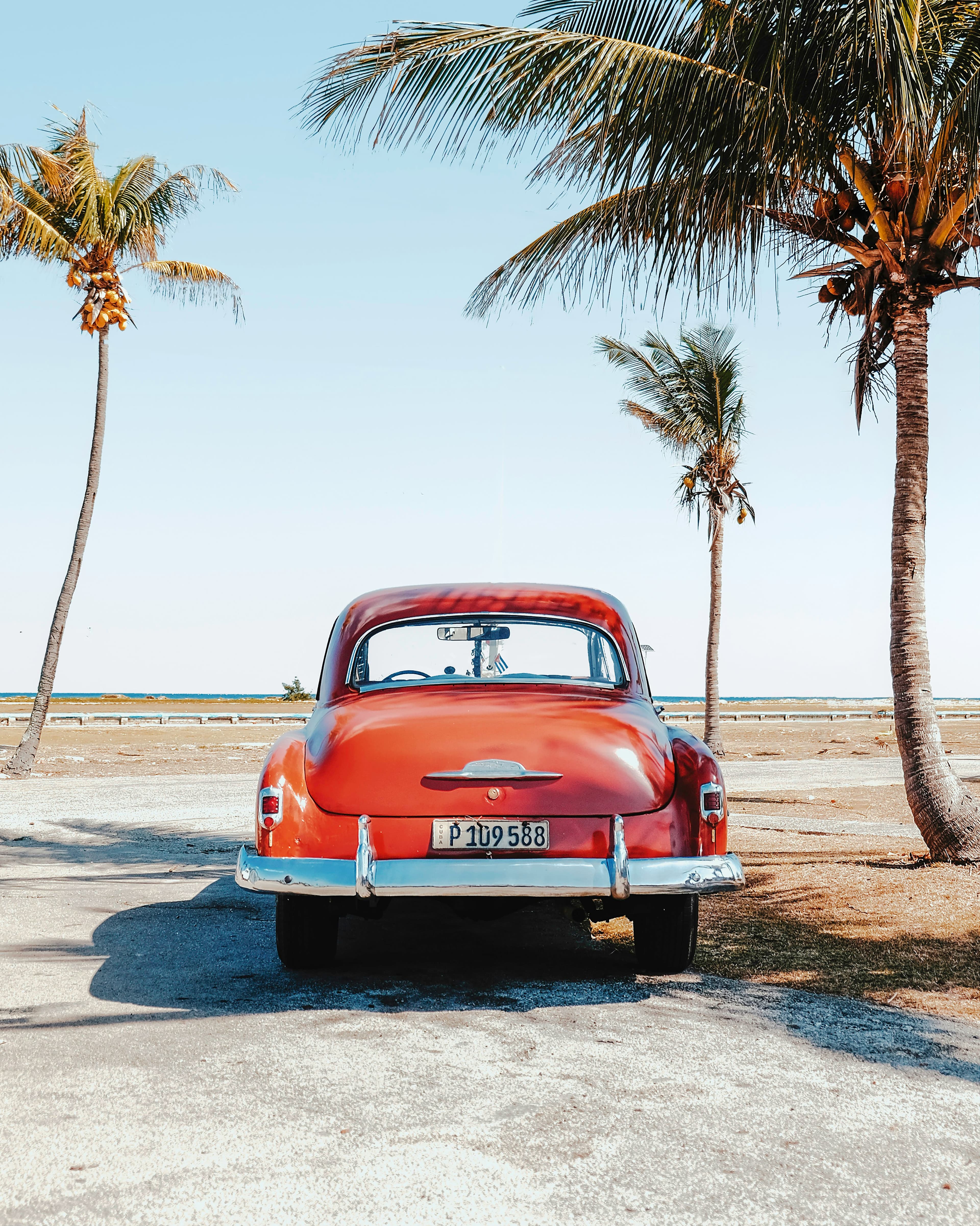 Vintage red car under palm trees